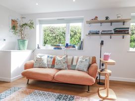 A living room with a sofa, bookshelf, and plant at Hillbre in Trevone