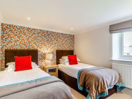 A bedroom with two beds and a lamp at Summerleaze Cottage 2 Spa in Bude