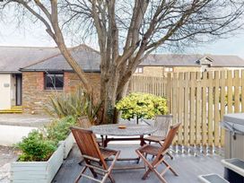 A garden with a table and chairs under a tree at Summerleaze Cottage 2 Spa in Bude
