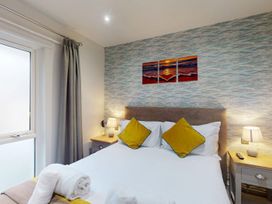 A bedroom with a bed and artwork on the wall at Summerleaze Cottage 2 Spa in Bude