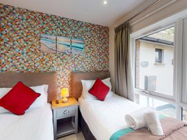 A bedroom with two beds and a bedside table at Summerleaze Cottage 2 Spa in Bude