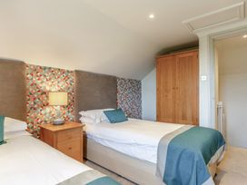 A bedroom with two beds and a bedside table at Summerleaze Cottage 2 Spa in Bude