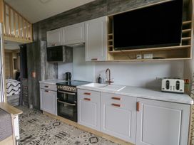 A kitchen with cabinets, sink, and appliances at The Family Pod in Swansea