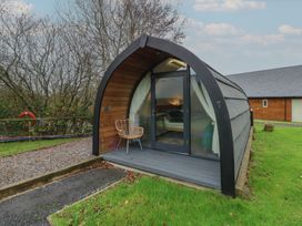 A cabin with a glass door and chair outside at Garden Lodge 1 Swansea