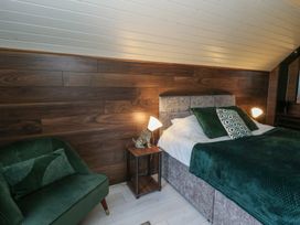 A bedroom with a bed and chair at Garden Lodge 2 Swansea