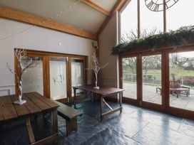 A dining room with wooden tables and sliding doors at Garden Lodge 2 Swansea