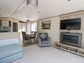 A living room with a television and dining area at Altair Lodge