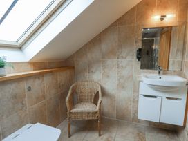 A bathroom with a sink, toilet, chair, and shelf at Oak Tree Cottage in Swansea