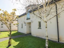 An exterior view of a cottage with a path and trees at Oak Tree Cottage in Oldwalls, Llanrhidian, Gower
