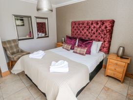 A bedroom with a bed and chair at Oak Tree Cottage Oldwalls, Llanrhidian, Gower