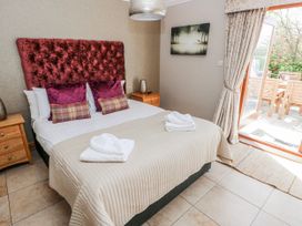 A bedroom with a bed and patio access at Oak Tree Cottage in Oldwalls, Llanrhidian, Gower