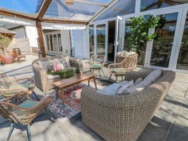A conservatory with seating and a table at Oak Tree Cottage Oldwalls, Llanrhidian, Gower