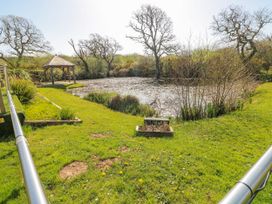 A garden with a pond and gazebo at Oak Tree Cottage Oldwalls, Llanrhidian, Gower