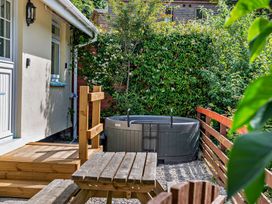 A garden with a hot tub and wooden furniture at Kernow Nook Spa, Perranporth