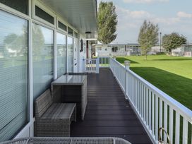 An outdoor patio with a table and chairs at No.49 Cherry Park in Chapel St Leonards