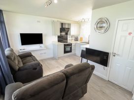 A living room with a sofa and kitchen area at No.49 Cherry Park in Chapel St Leonards