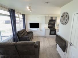 A living room with a sofa and television at No.49 Cherry Park in Chapel St Leonards