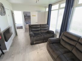 A living room with sofas and a door at No.49 Cherry Park in Chapel St Leonards