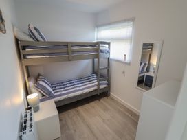 A bedroom with a bunk bed and a mirror at No.49 Cherry Park in Chapel St Leonards