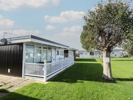 A house with a fence and tree in the outdoor area at No.49 Cherry Park, Chapel St Leonards
