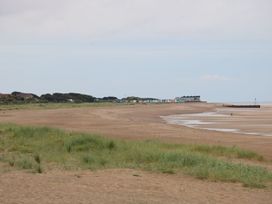 A beach with huts in the background at No.49 Cherry Park, Chapel St Leonards