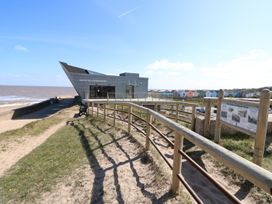 A building near the beach with a path and fence at No.49 Cherry Park in Chapel St Leonards