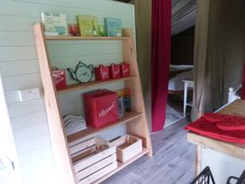 A shelf with containers and a clock in a kitchen at Ceri in Newcastle Emlyn