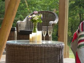 An outdoor seating area with a chair, table, flowers, and candles at Ceri in Newcastle Emlyn