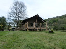 A tent structure with a deck and chairs at Ceri in Newcastle Emlyn