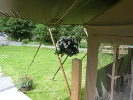 A tent structure with a hanging flower basket at Ceri in Newcastle Emlyn