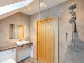 A bathroom with a mirror, shower, sink, and door at Tranquillity 3 in Warton near Carnforth