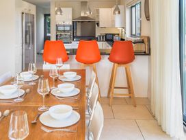A kitchen with bar stools and a dining table at Nan's House Spa in Marhamchurch