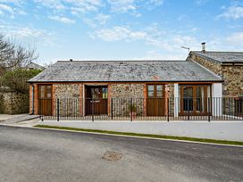 A house with a stone exterior and fence at Barley Park in Marhamchurch