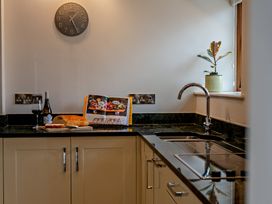 A kitchen with a clock and countertop items at Barley Park in Marhamchurch