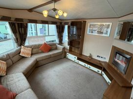 A living room with a sofa and electric fireplace at Wyreside Lakes - Holiday Accommodation 17442, Lancaster