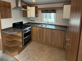 A kitchen with stove, sink, and cabinets at Wyreside Lakes - Holiday Accommodation 17442, Lancaster