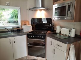 A kitchen with a gas stove and microwave at Aberdunant Hall Holiday Park - Holiday Accommodation 21897 Porthmadog