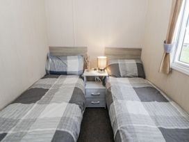 A bedroom with two beds and a nightstand at Brynowen Holiday Park - Holiday Accommodation 22432, Borth