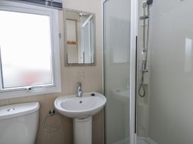 A bathroom with a sink, toilet, shower, and mirror at Brynowen Holiday Park - Holiday Accommodation 22432 Borth