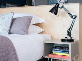 A bedroom with a bed, nightstand, lamp and books at The Weir in North Berwick