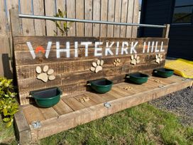 A wooden outdoor dog station with water bowls and paw prints at Whitekirk Hill North Berwick