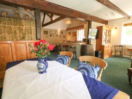 A dining room with a table, chairs, and flowers at The Old Barn in Stourton Caundle near Stalbridge