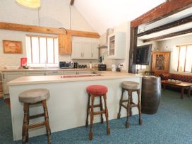 A kitchen with bar stools and cabinets at The Old Barn in Stourton Caundle near Stalbridge