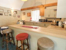 A kitchen with bar stools and cabinets at The Old Barn in Stourton Caundle near Stalbridge