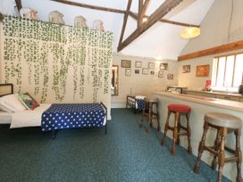 An open plan living area with a bed and a bar counter at The Old Barn in Stourton Caundle near Stalbridge