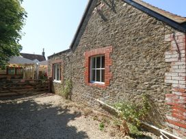A stone wall with a window and gravel area at The Old Barn in Stourton Caundle near Stalbridge