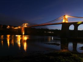 A bridge over water with lights reflecting at New build at Tyn Pwll in Llanfairpwllgwyngyll