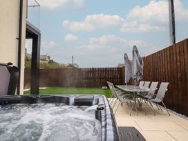 A garden with a hot tub and dining table at Pistyll Ddu in Brynsiencyn near Llanfairpwllgwyngyll