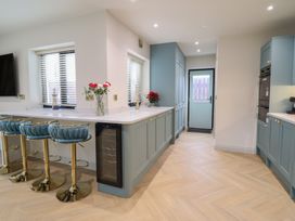 A kitchen with bar stools and a wine cooler at Pistyll Ddu in Brynsiencyn near Llanfairpwllgwyngyll
