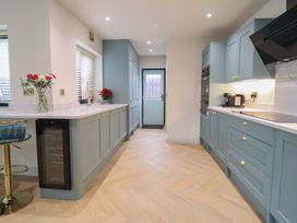 A kitchen with a wine cooler and bar stools at Pistyll Ddu in Brynsiencyn near Llanfairpwllgwyngyll